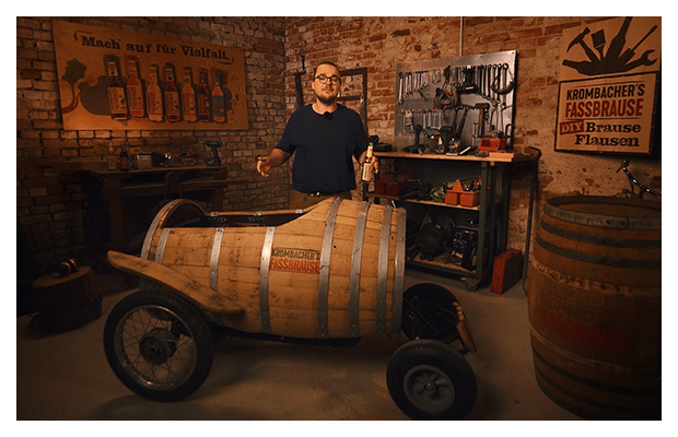 Fassbrause Mobil steht in rustikalem Raum. Mann steht da hinter