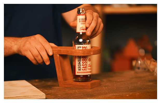 Ein Getränkehalter aus Holz mit einer fassbrause drin.
