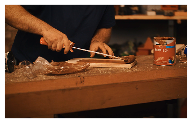 Holzplatten werden mit einer Malerrolle lackiert.