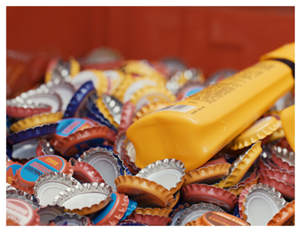 Gelbe Klebertube liegt in Kronkorken