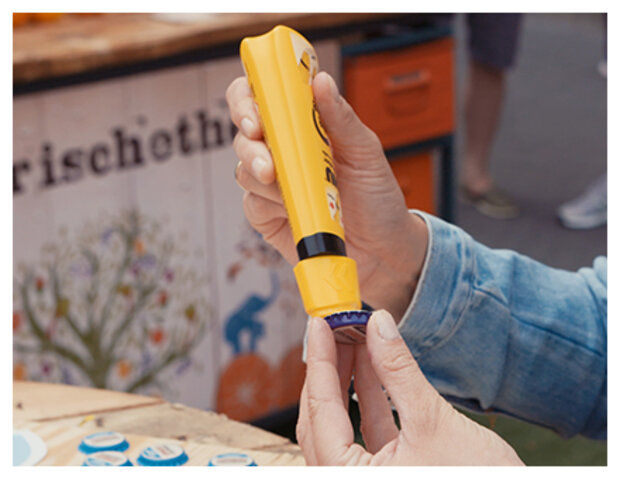 Eine Hand hält einen gelben Flüssigkleber