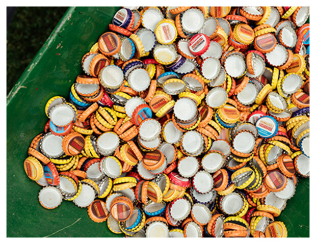 Bunte Kronkorken in grünem Behälter