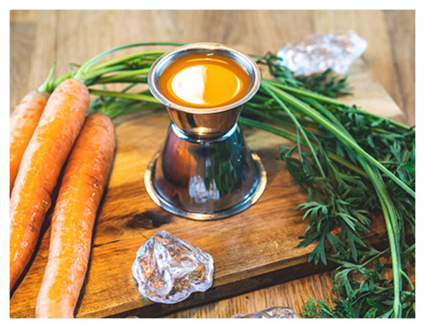 Karottensaft in Eierbehälter auf einem Holzbrett