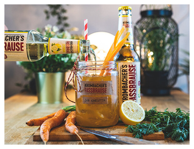 Drinkglas mit Fassbrause Zitrone mit Karottenmix. Eine Flasche schenk Fassbrause ins Glas