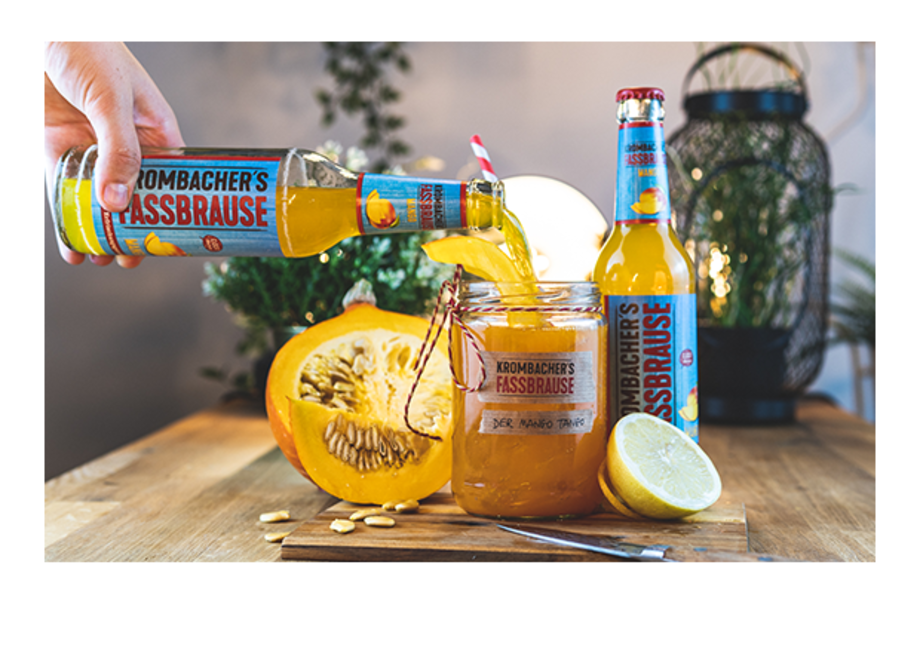 Fassbrause Mango mit Cocktailglas und Mangofrüchten und Text: Mango-Tango