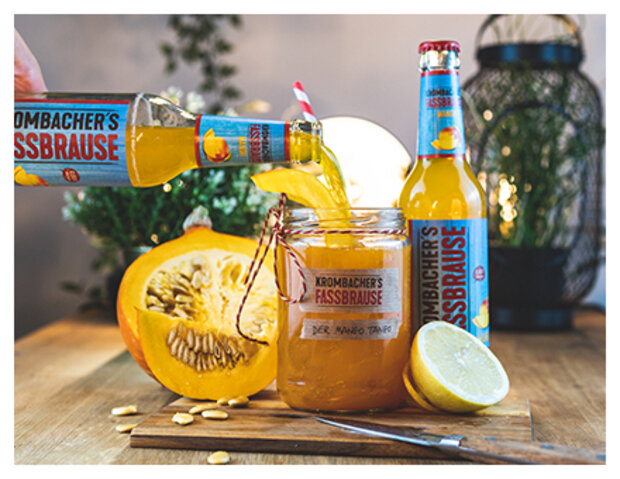 Fassbrause Mango mit Cocktailglas und Mangofrüchten und Text: Mango-Tango