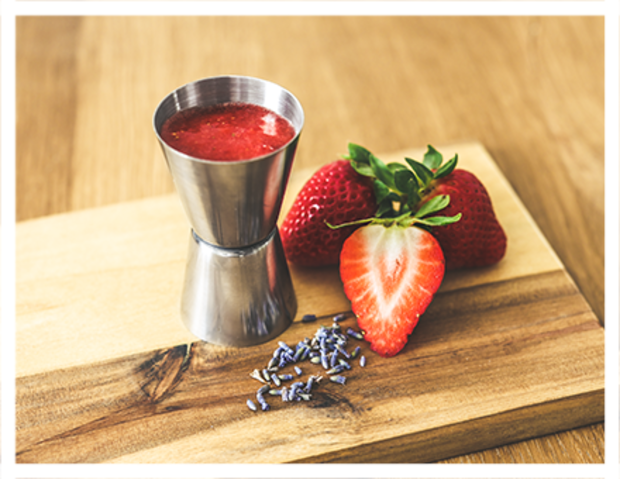 Erdbeerpüree in Behälter und losen Erdbeeren.